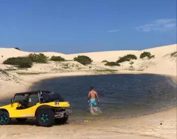 Buggy e pessoa num lago entre as dunas